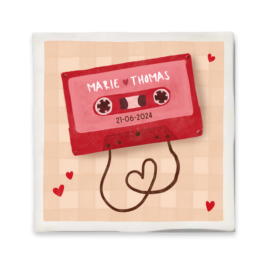 Gepersonaliseerd tegeltje met illustratie van een rood cassettebandje. Het lint van het bandje vormt een hartje en rondom zijn kleine rode hartjes te zien. Achtergrond in zachtroze ruitpatroon.